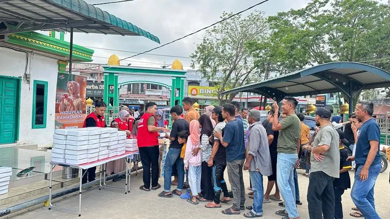 Relawan FOI membagikan paket hidangan berbuka puasa Teh Celup Sosro kepada warga yang mengantre di halaman masjid komunitas